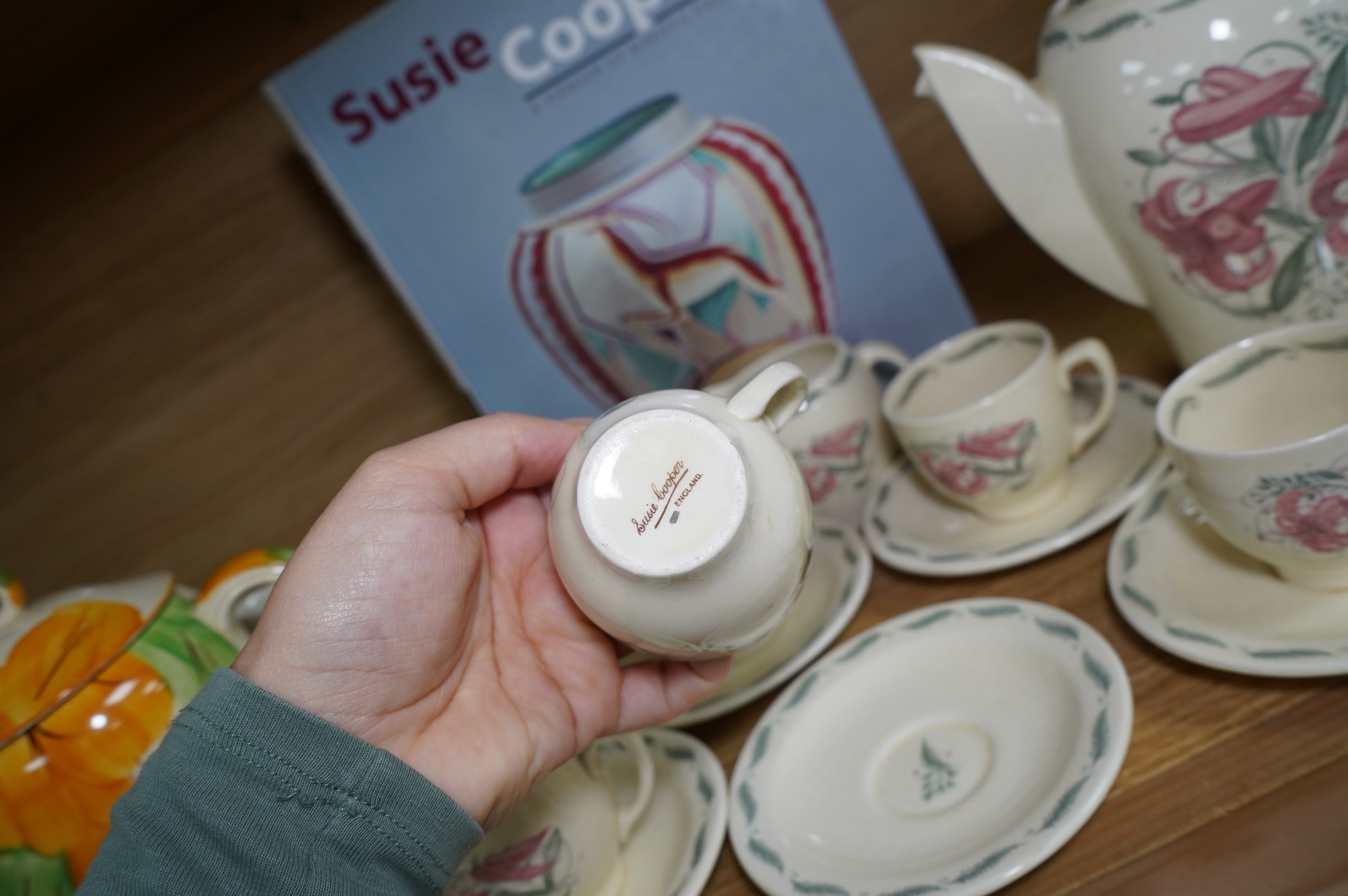 A Susie Cooper style 'Tiger Lily' pattern teaset, possibly by Wood & Co., a Susie Cooper reference book and a later painted Falcon shape coffee pot. Condition - good
